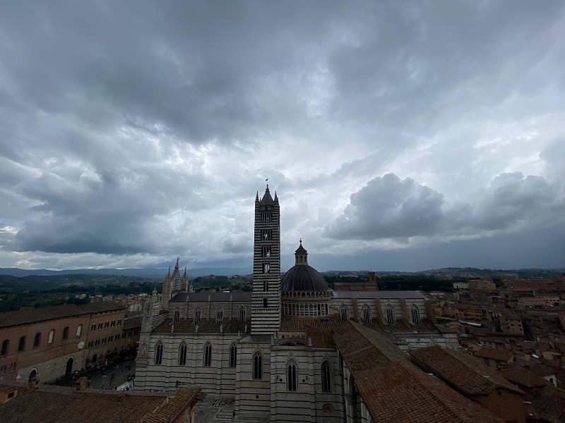 A wide view of Duomo di Siena on a dark and cloudy day
