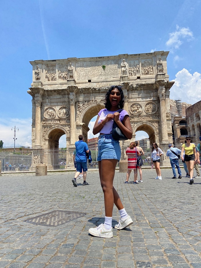 A CET Siena student standing in front of the Arch of Constantine in Rome, Italy with other tourists surrounding the Arch