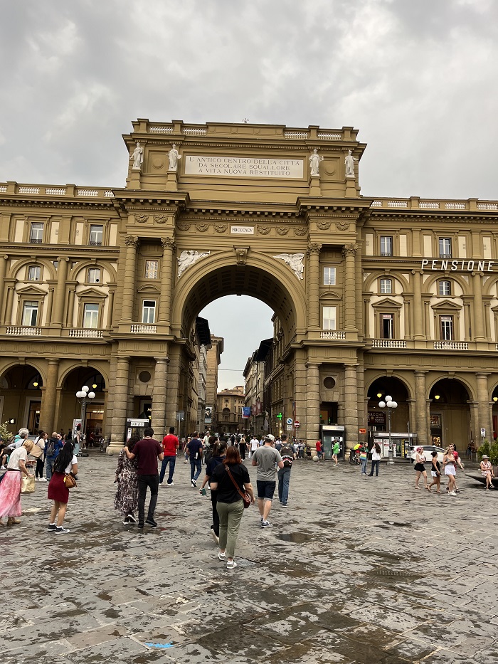 Street view of people and the Arcone Triumphal Arch in Piazza della Repubblica