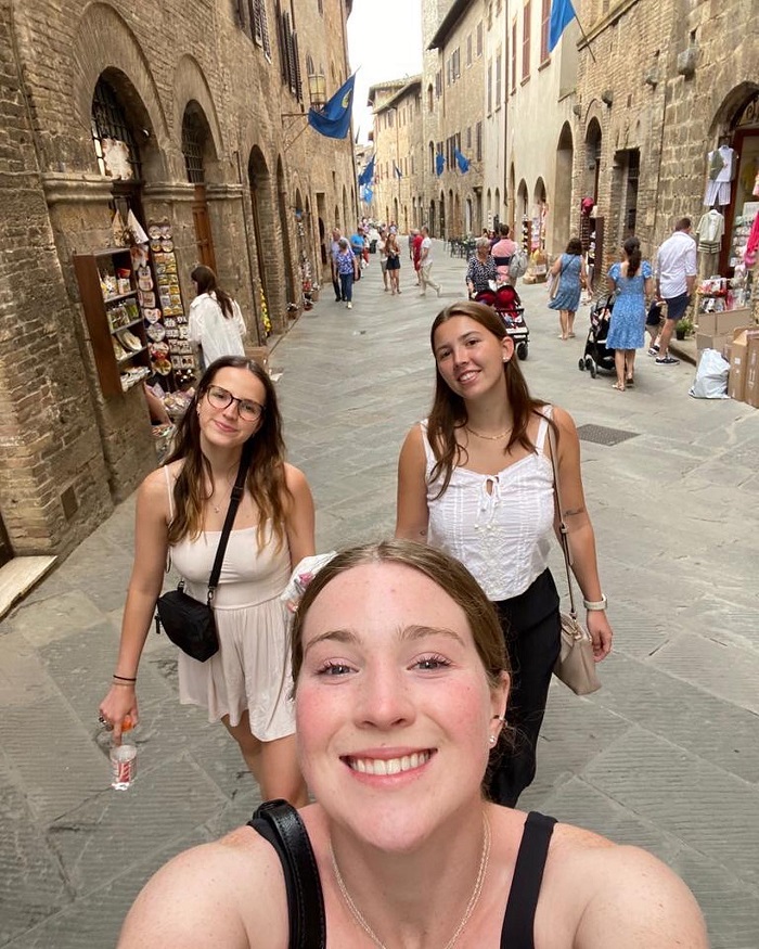 Three CET Siena students smiling while walking in a street in San Gimignano