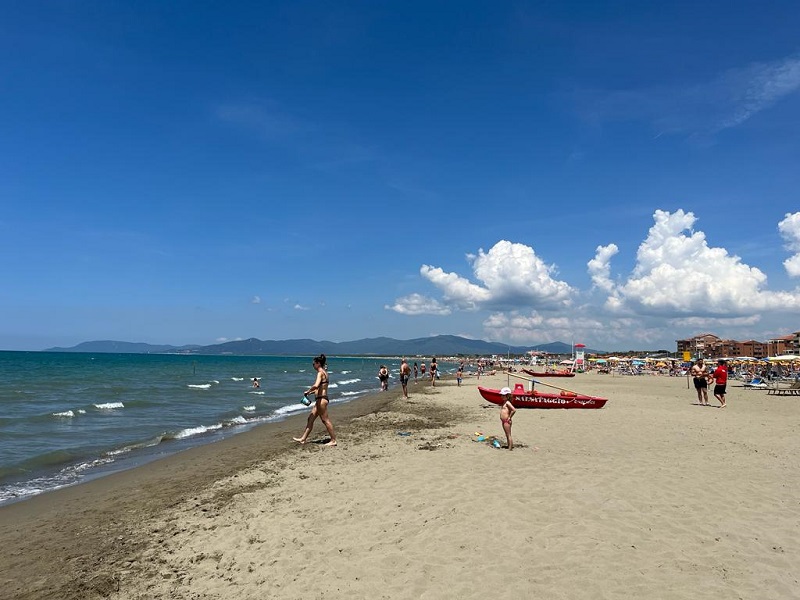 People in bathing suits on a beach in Marina di Grosseto on a partly cloudy day