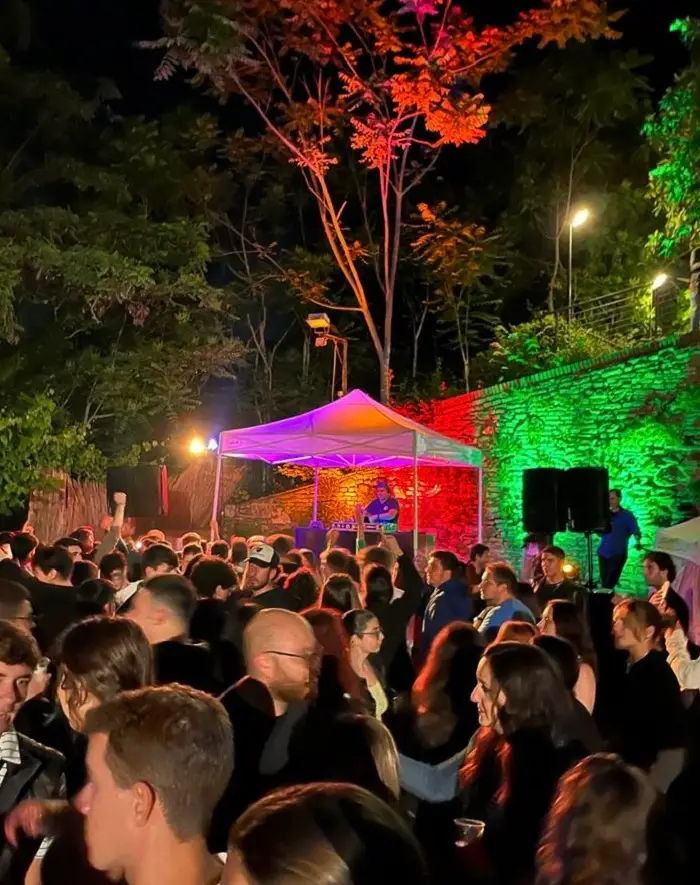 Many people crowded in an outdoor space with neon lights lit up in Italy