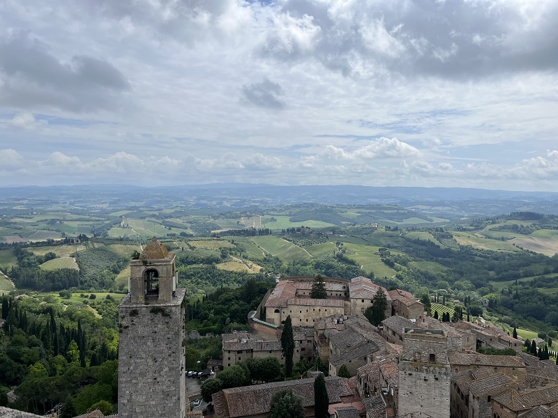 The view from the top of Torre Grossa of rolling green hills and clouds in the sky in Siena, Italy