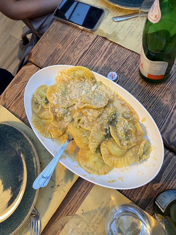 Cooked ravioli on a platter and empty dishes next to the platter