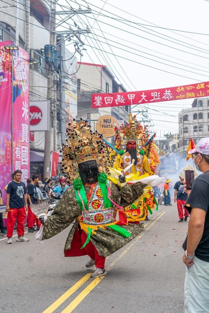 People wearing extravagant costumes while in the middle of the road for the Dajia Mazu Pilgrimage festival held in Taiwan