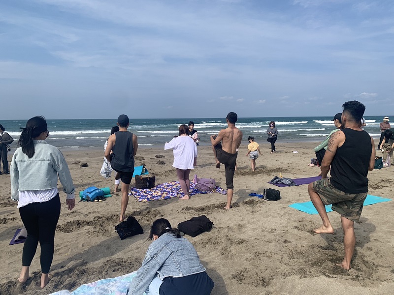 People standing on one leg during a beach yoga activity in Keelung, Taiwan