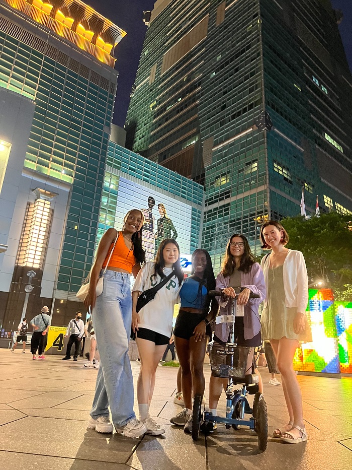 A group of five girls standing in the center of tall skyscraper buildings in Taiwan