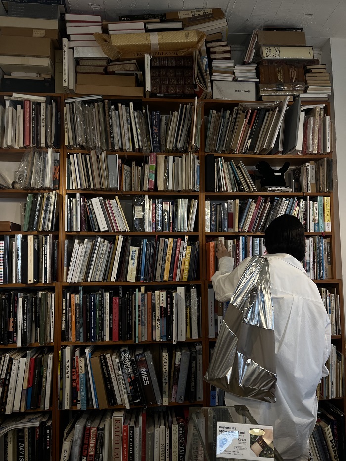 A female AICAD in Japan student browsing through books among shelves in a bookstore