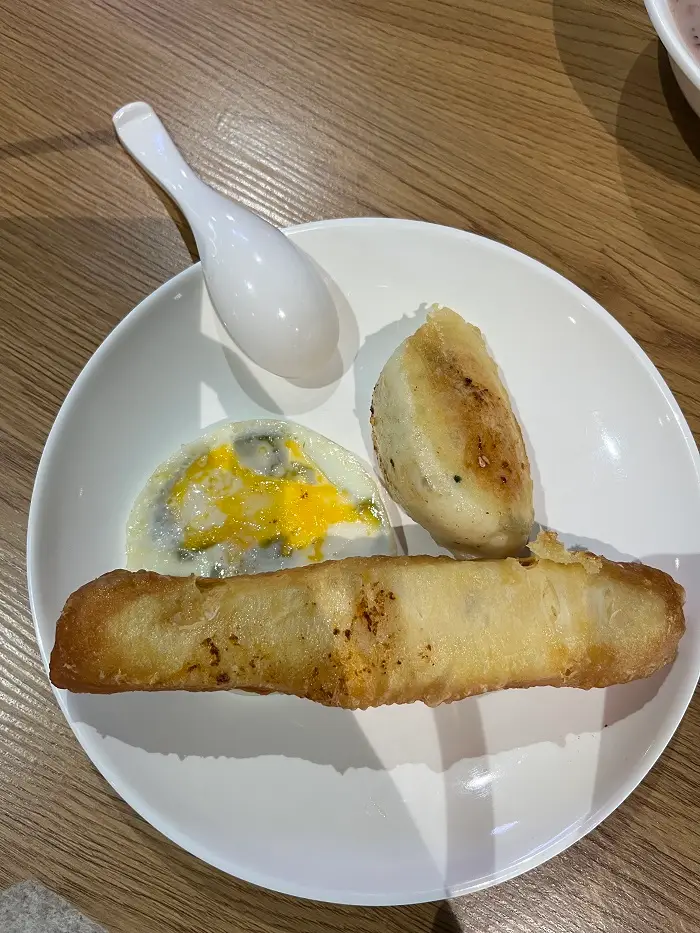 Deep-fried dough, an egg, and pan-fried buns on a plate
