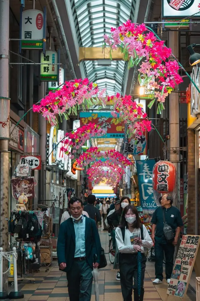 People walking in a street between stores and shops in Janjan-Yokocho near Shinsekai