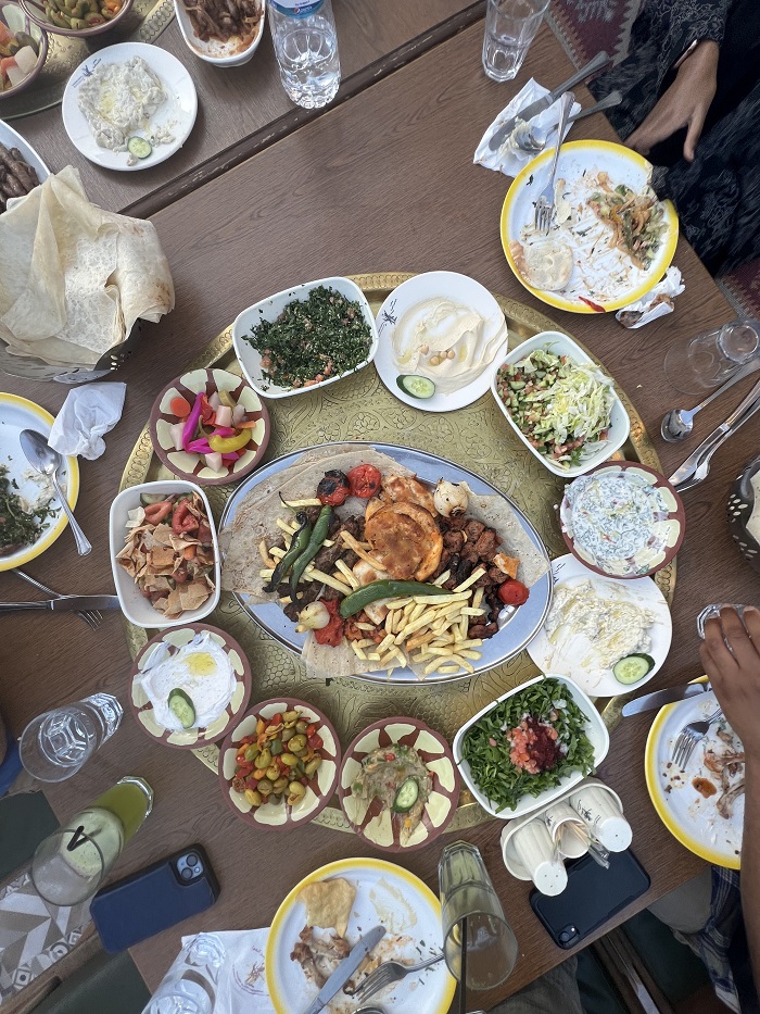 A large food spread of typical Jordanian dishes including many vegetables, hummus, and meats
