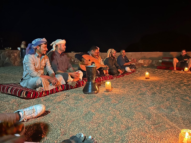 The Bedouins playing music for CET Jordan students while sitting on the floor with candles lit at night