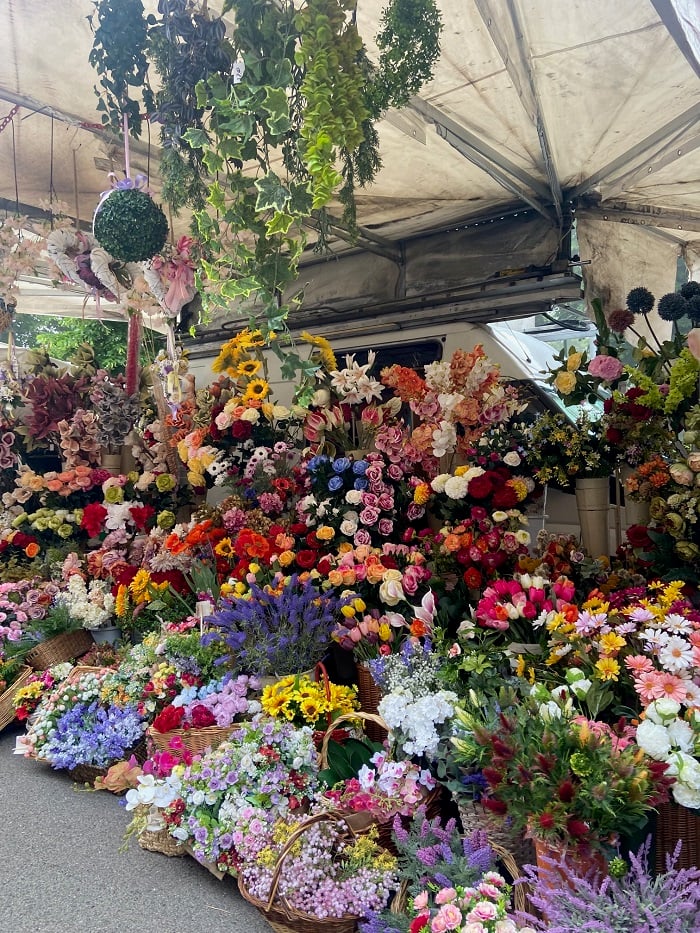 A large variety of flowers at a stand in a outdoor market in Siena, Italy