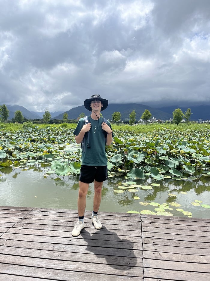 A CET Taiwan student posing and smiling in front of Dapo Pond on a cloudy day
