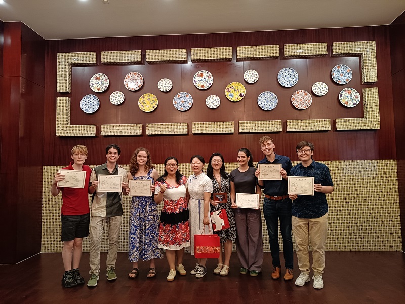 The CET Beijing Chinese 400 class holding their graduation certificates after completing the program alongside professors