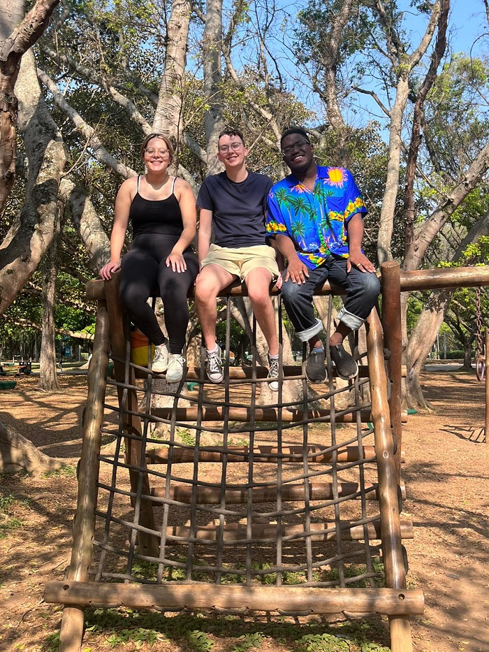 Three CET Brazil Social Justice students sitting on top of something in Ibirapuera Park