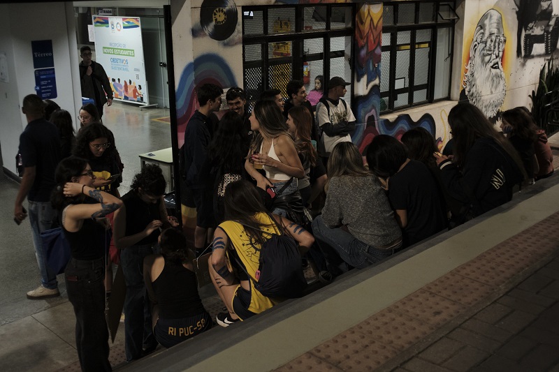 A group of Pontifícia Universidade Católica de São Paulo students chatting and interacting on campus at night