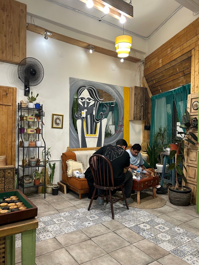 Two people sitting by a small table inside of Zghairon café decorated with plants and art on the first floor in Jordan 