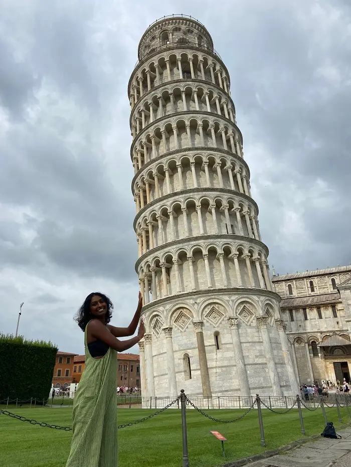 A CET Siena student posing by the leaning Tower of Pisa on a cloudy day outdoors