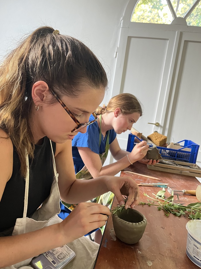 Two CET Siena students decorating their clay pots inside an art studio