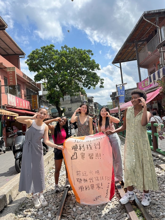 CET Taiwan students and roommates holding up a large lantern with Chinese writing in the middle of a street in Taiwan