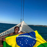 student smiling on boat holding brazil flag