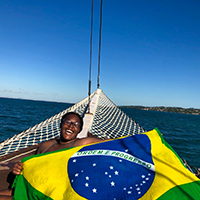 student smiling on boat holding brazil flag