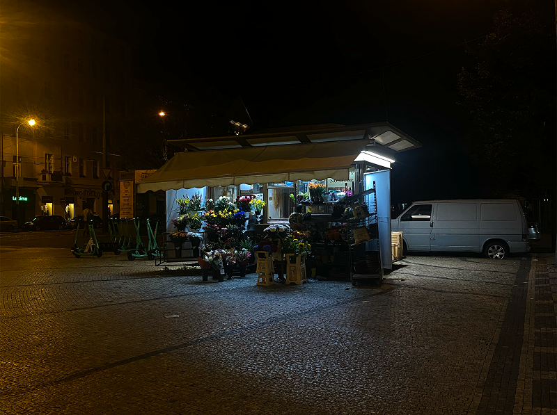 A lit up flower market stand at night in Prague