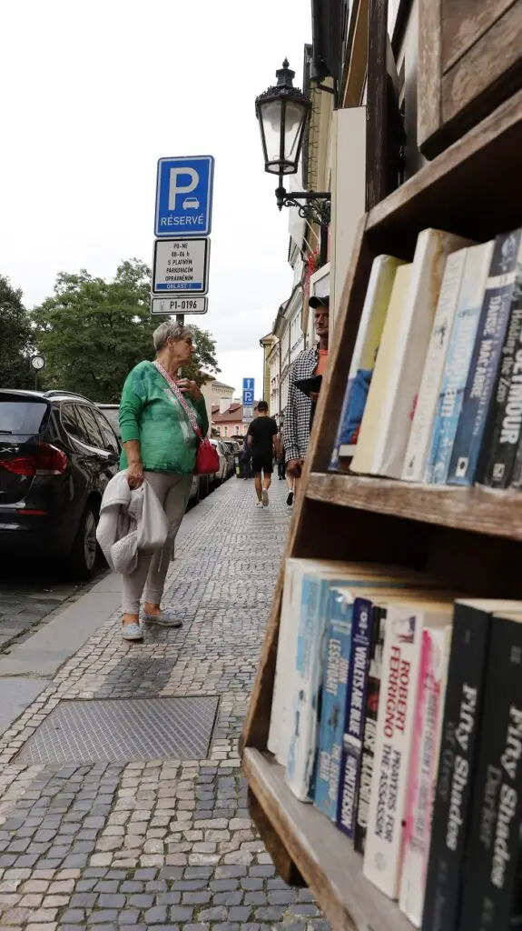 A woman standing by a bookshelf outside on a street in Prague, Czech Republic