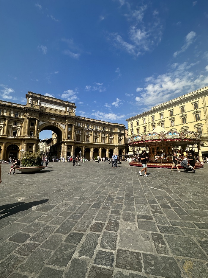 A square in Florence, Italy with many people and a carousel 