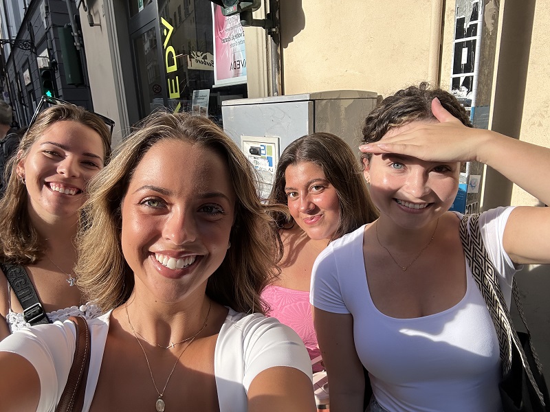 Four CET Florence students smiling by a store in Florence, Italy on the way to class