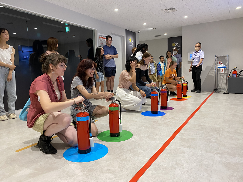 A small group of CET Japan students holding fake fire hydrants in the Osaka City Abeno Life Safety Learning Center