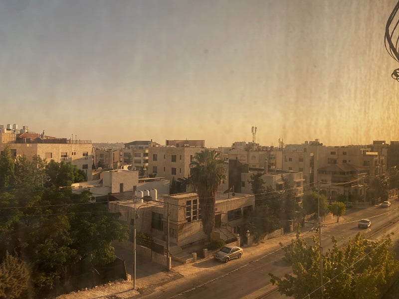 A view of a street in Amman, Jordan through a slightly dirty and yellow-stained yellow of an apartment