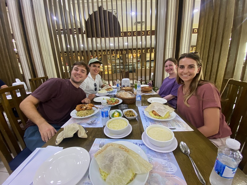 Four CET Jordan students sitting around a table with food at a restaurant called AlQuds AlJadeed in Amman, Jordan