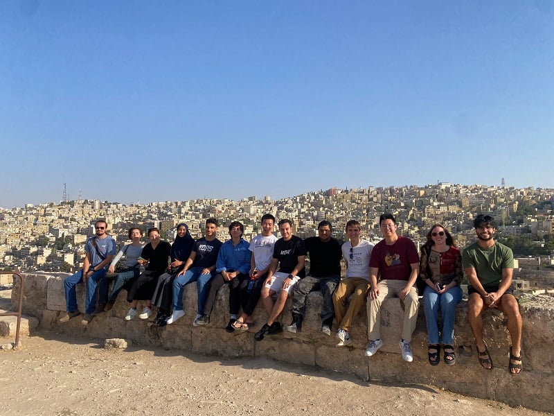 A large group of CET Jordan students sitting on the ledge with a lookout of the city 