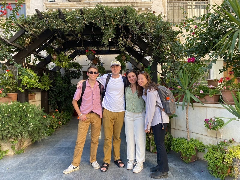 Four CET Jordan students smiling in a group by a floral arch outdoors in Jordan