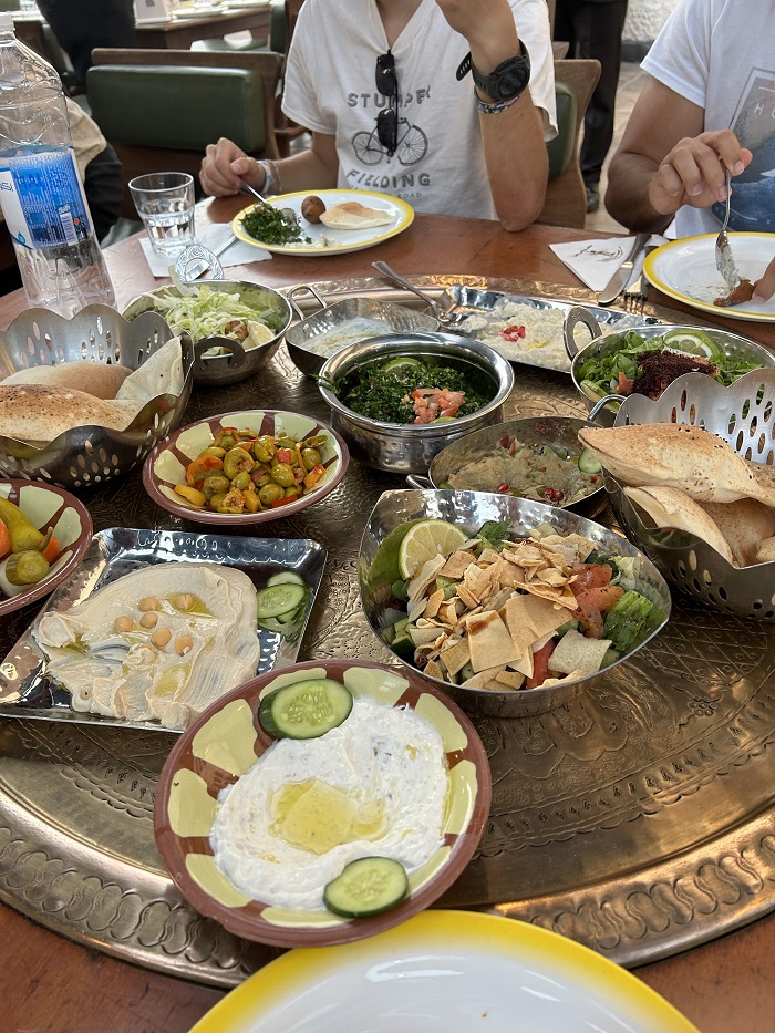 Multiple dishes with vegetables, hummus. bread, and more set on the table at the Tawaheen al-Hawa restaurant 