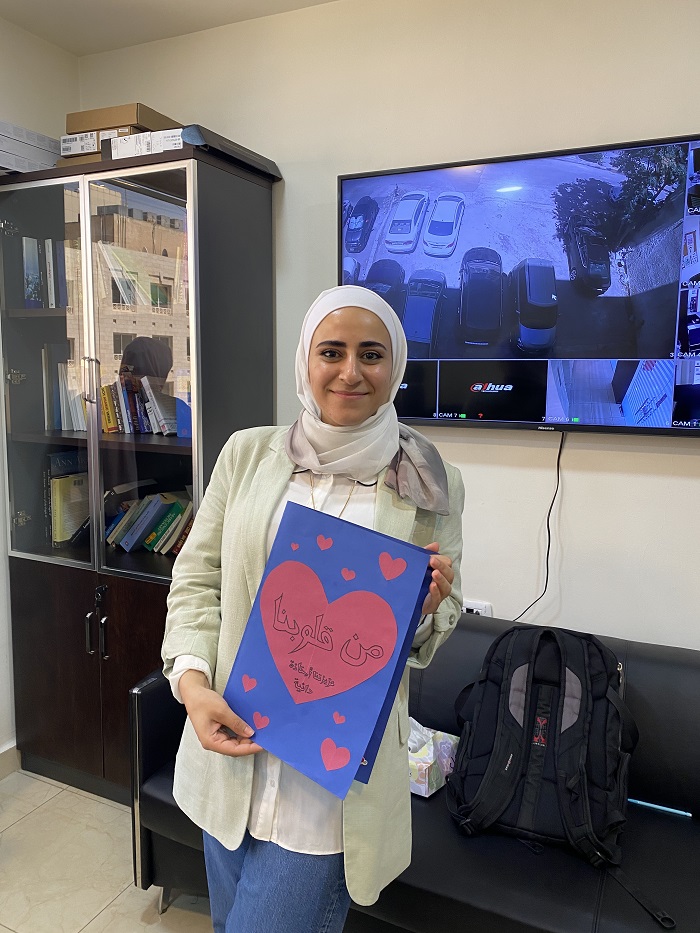 A CET Jordan teacher, Dania, holding a handmade card from her students