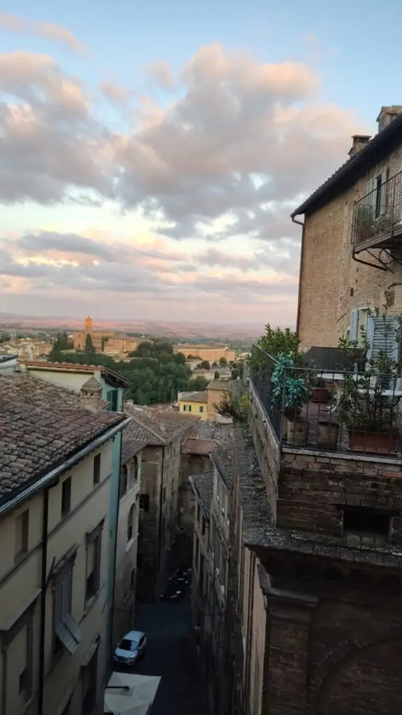A view of a narrow street in Siena, Italy with buildings layered on both sides