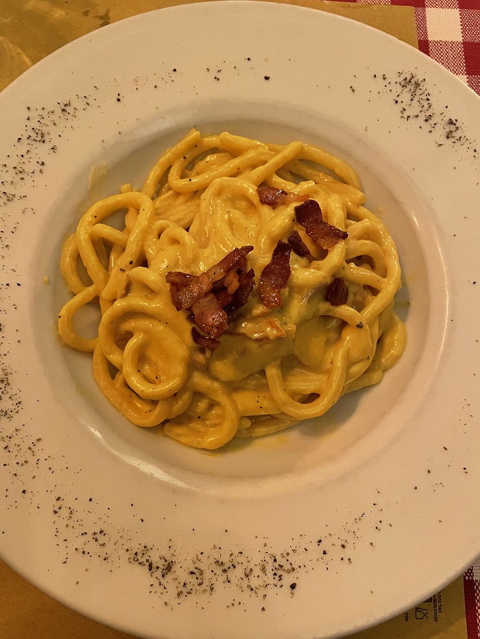 Pici Alla Carbonara with pepper sprinkled around the plate