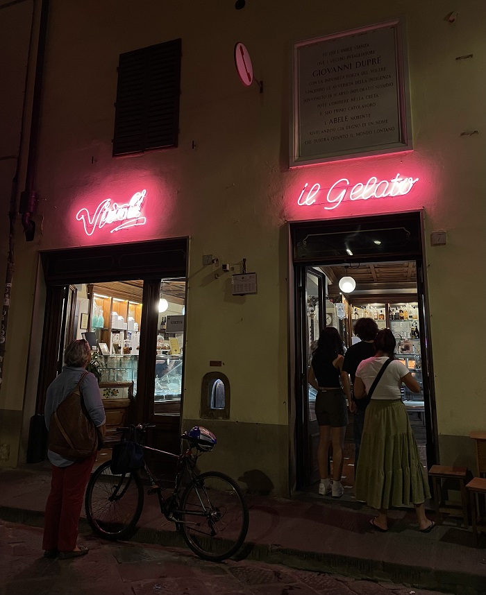 People ordering gelato at night under Vivoli’s neon sign in Florence, Italy