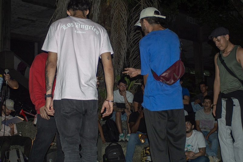 People gathered outdoors at a freestyle rap event at night