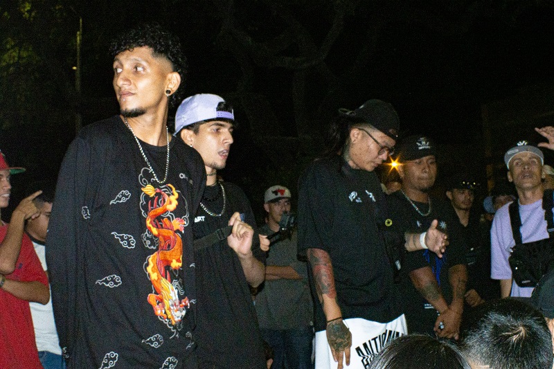 People gathered outdoors at a freestyle rap event at night