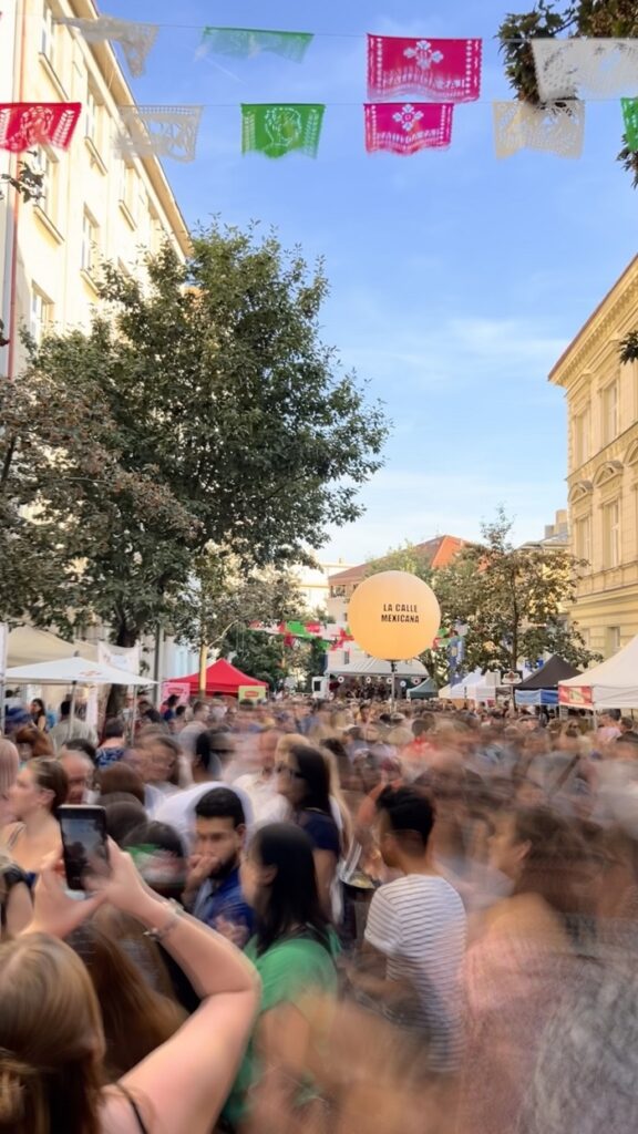 A crowded street with blurry people moving in the Mexican street festival in Prague on a cloudless day