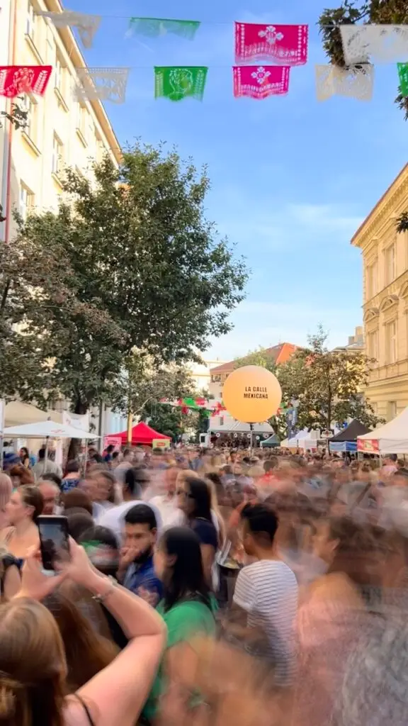A crowded street with blurry people moving in the Mexican street festival in Prague on a cloudless day