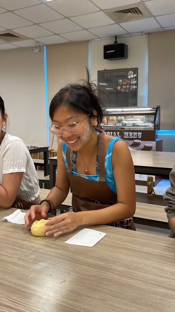 A CET Taiwan student laughing while making a mooncake with flour on her cheeks