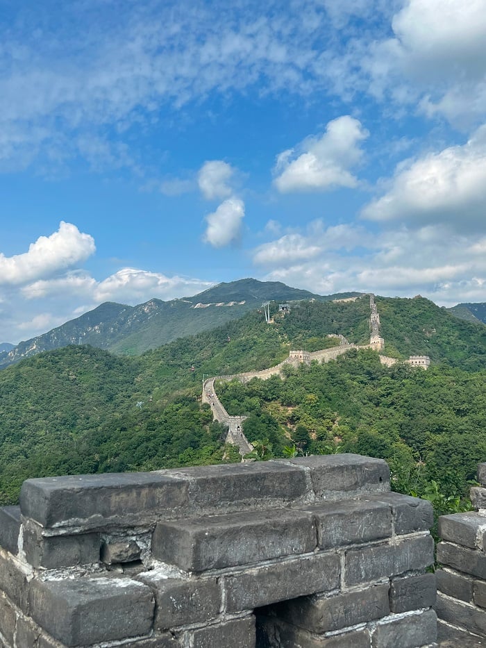 Scene of the Great Wall at a distance, atop the green mountains and blue sky
