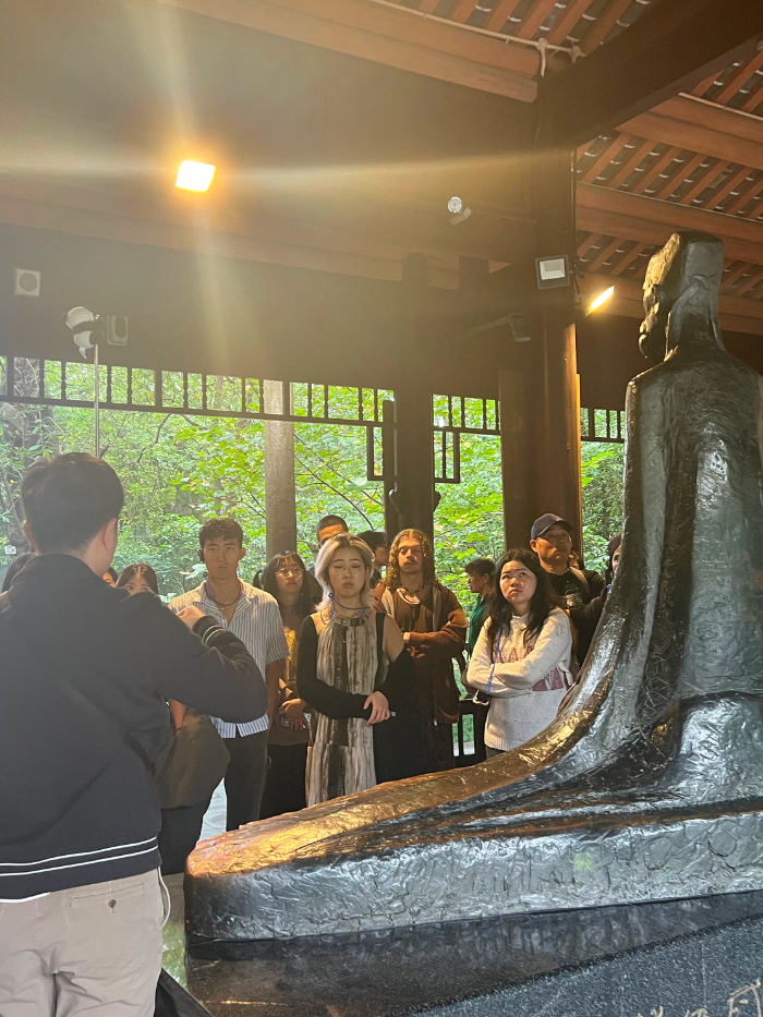 A tour guide offering knowledge on the life of the Tang dynasty poet, Du Fu, while standing by a statue of the writer in Chengdu
