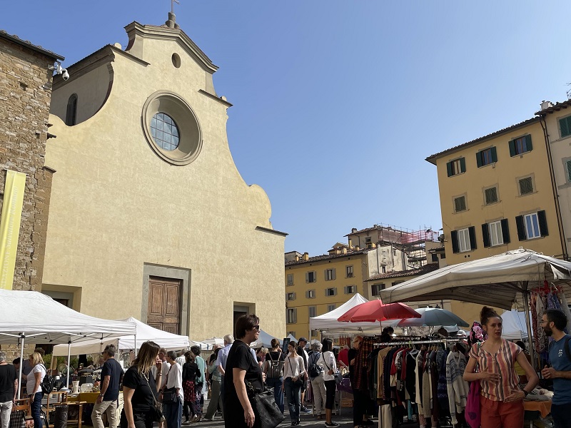 Tents set up outdoors in Piazza Santo Spirito with tourists and locals in Florence, Italy