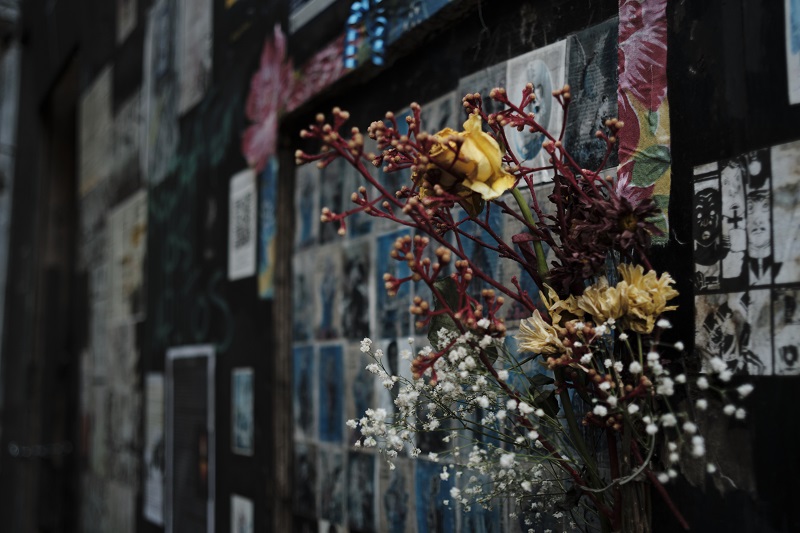 Artwork, writing, and flowers posted near a chapel in São Paulo, Brazil in respect and remembrance of this history